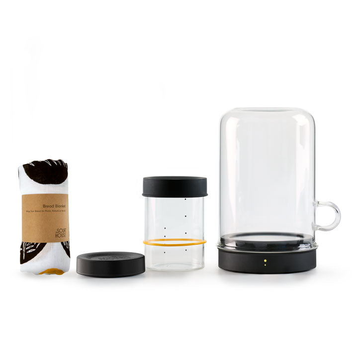 Set of sourdough tools on a white background including: glass sourdough container with black lid, gold and black bread blanket and a Goldie by Sourhouse